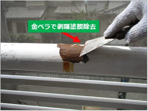 戸建て住宅バルコニー手すりの古い塗膜を金ベラで剥がしている状況