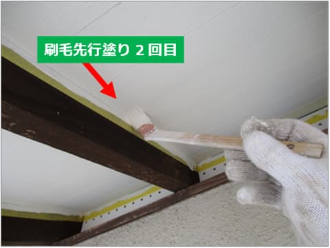 戸建て住宅の軒天塗装の2回目を刷毛で塗装している状況