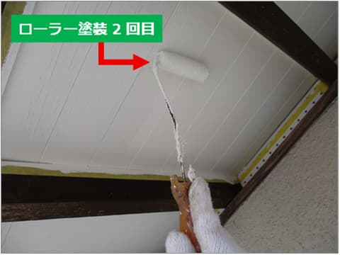 戸建て住宅の軒天塗装の2回目をローラーで塗装している状況