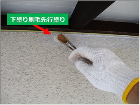 戸建て住宅の外壁に刷毛で下塗り塗料を塗装している状況