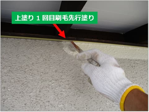 戸建て住宅の外壁に刷毛で中塗り塗料を塗装している状況