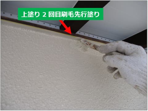 戸建て住宅の外壁に刷毛で上塗り塗料を塗装している状況