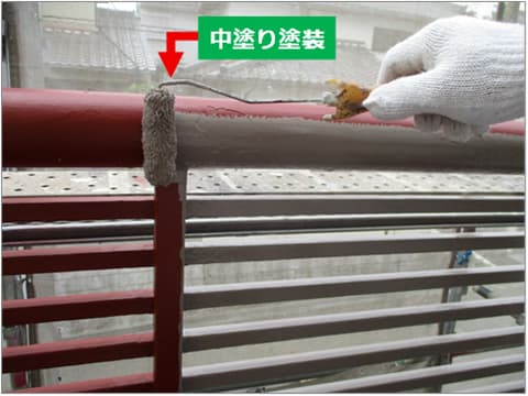 戸建て住宅のバルコニー手すりに中塗り塗料を塗装している状況