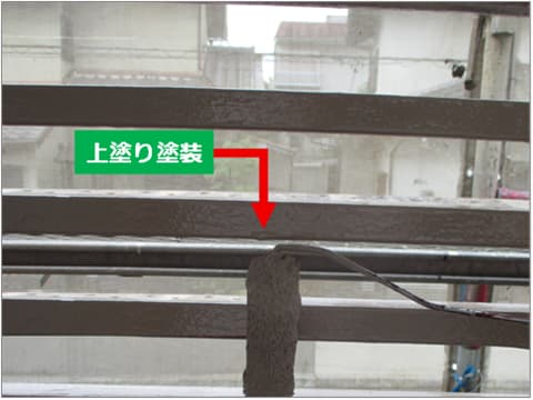 戸建て住宅のバルコニー手すりに上塗り塗料を塗装している状況