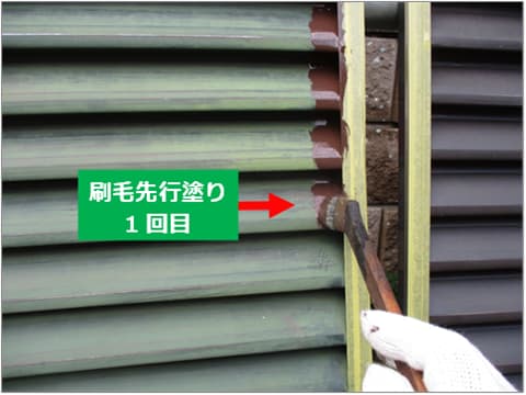 戸建て住宅の雨戸に刷毛で中塗り塗料を塗装している状況