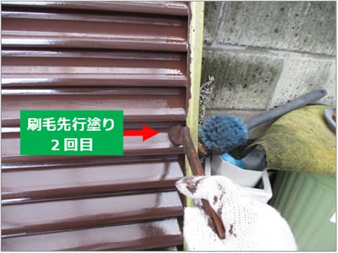 戸建て住宅の雨戸に刷毛で上塗り塗料を塗装している状況
