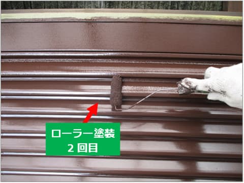 戸建て住宅の雨戸にローラーで上塗り塗料を塗装している状況