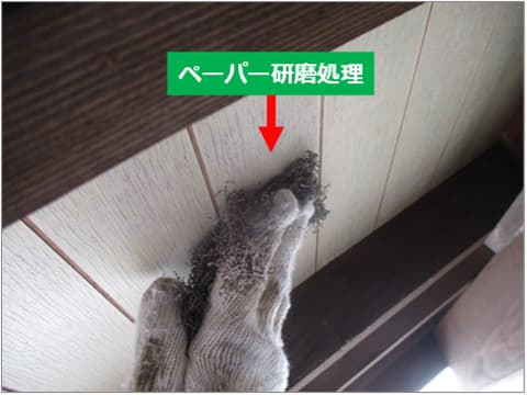 戸建て住宅軒天の古いプリント合板を手作業で研磨している状況
