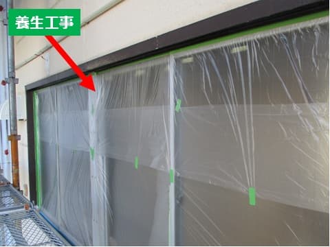 塗装現場の店舗の窓にビニール養生を施工している状況