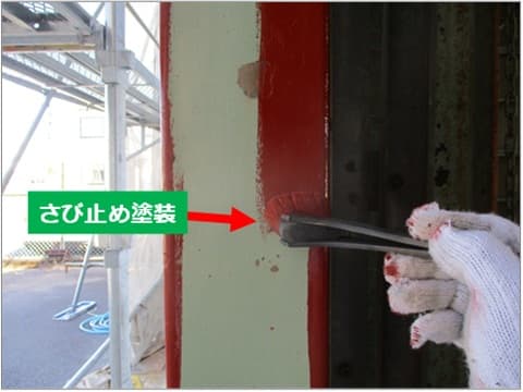 倉庫入り口の鉄骨に刷毛で錆止め塗装を施工している状況状況