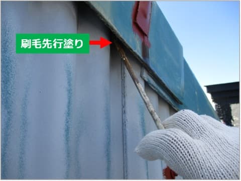 スレート外壁と屋根の隙間を細い刷毛で塗装している状況