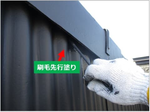 スレート外壁と屋根の隙間を刷毛で塗装している状況