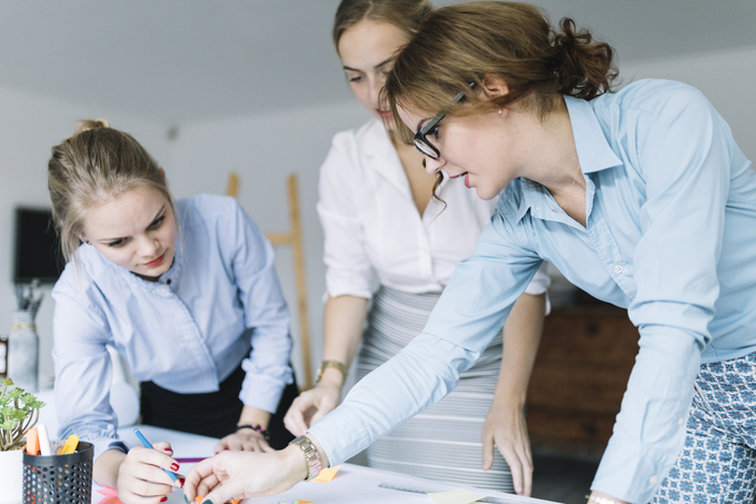 Drei Projektmitarbeiterinnen bei konzeptioneller Gestaltung am Schreibtisch.